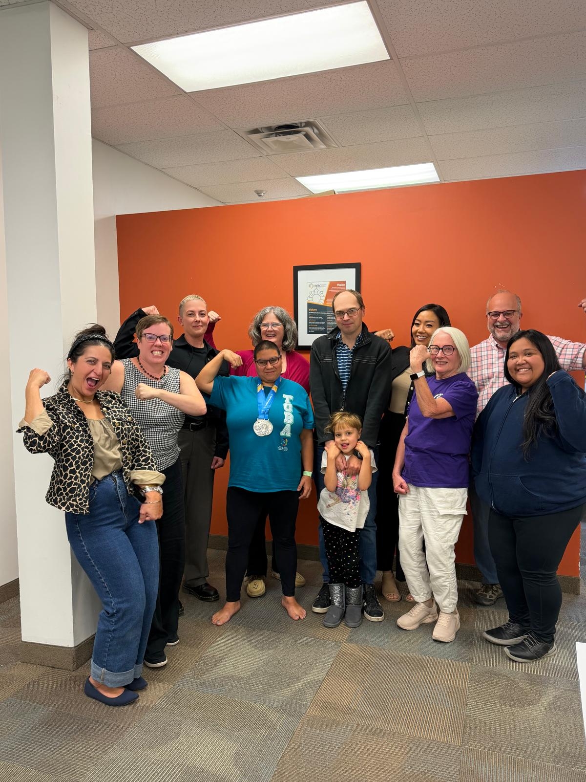 Katie wearing one of her silver medals, surrounded by her family and members of the Epic Opportunities Foundation Board.